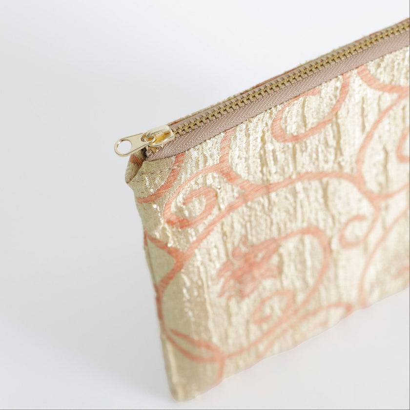 Gold pouch with pink floral pattern on a white background