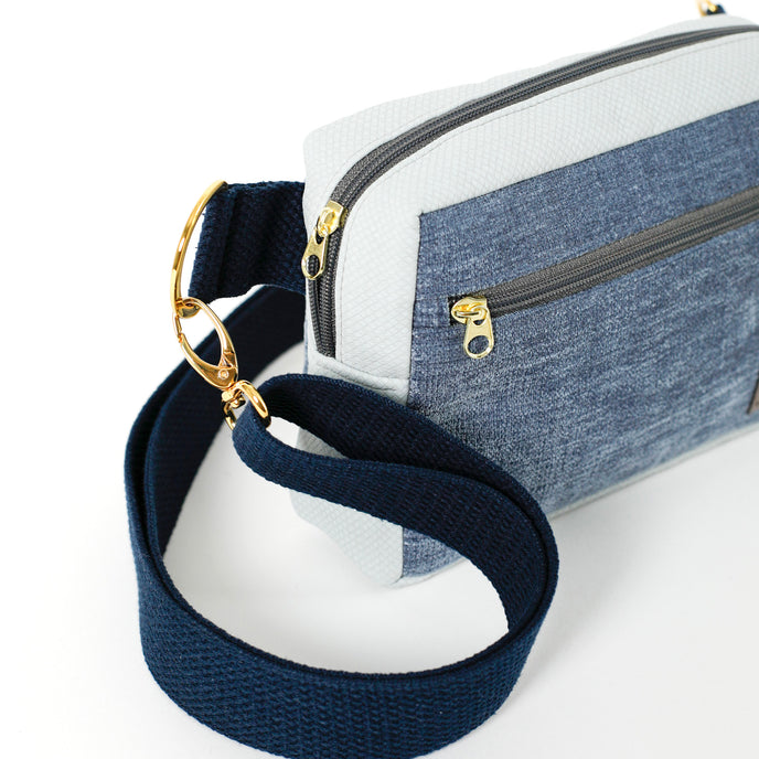 Close up of a gold zipper on a crossbody bag with a blue velvet exterior and blue cotton straps named after Kenya.