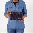 A woman holding a dark blue zip pouch with lines in multi-colors named after Keri 