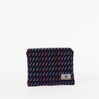 A dark blue zip pouch with a vibrant pattern of colorful short lines, featuring a zip closure and a label with a brand logo named after Keri