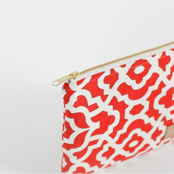 A red and white design zip pouch with a gold tone zipper named after Kesha