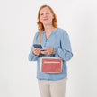 Woman holding a phone with a pink and white bag over her shoulder on a white background named after Korin 