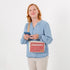 Woman holding a phone with a pink and white bag over her shoulder on a white background named after Korin 