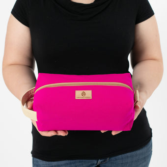 a woman holding a hot pink toiletry kit named after Kristen 
