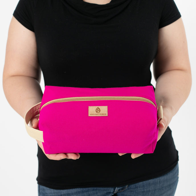a woman holding a hot pink toiletry kit named after Kristen 