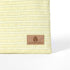 Tan suede Unshattered label on a light yellow striped zippered pouch on a white background