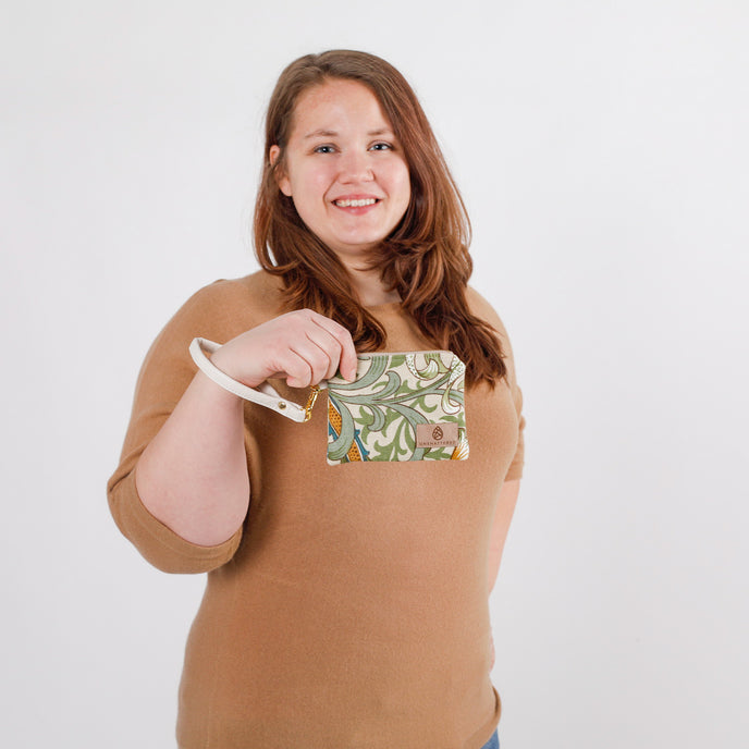 Person holding a floral-patterned clip pouch against a white background