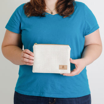 A woman holding a white woven design zip pouch named after Janelle