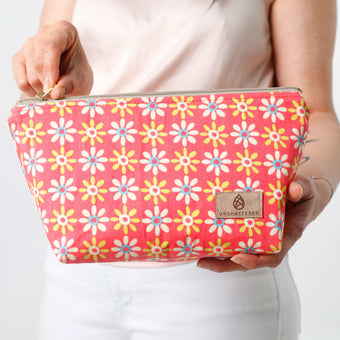 Floral patterned pouch held by a person with a visible brand logo named after Kristy 