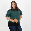 Woman holding brown luxury leather alternative clip pouch while wearing a green shirt on a white background