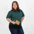 Woman holding brown luxury leather alternative clip pouch while wearing a green shirt on a white background