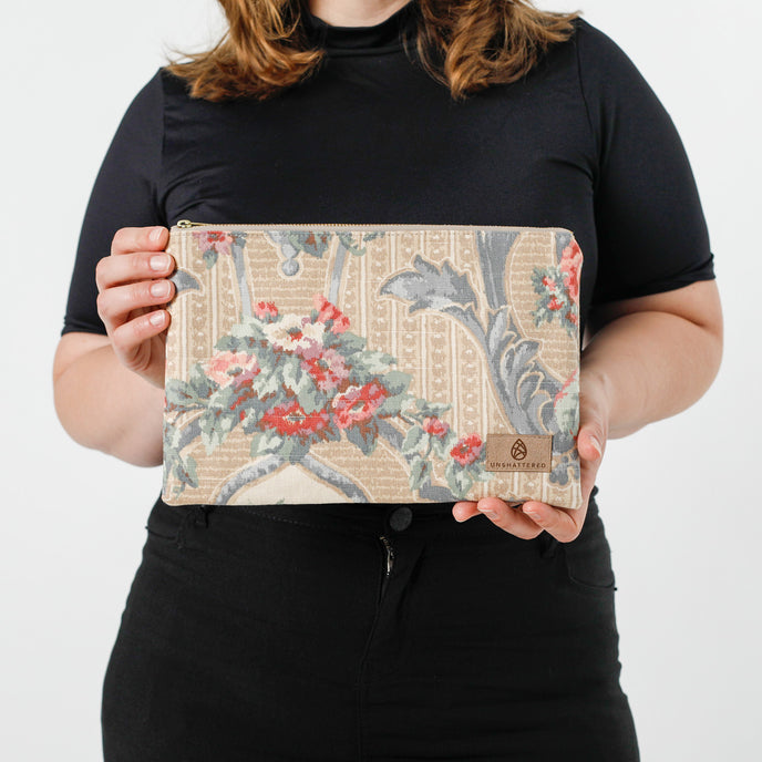 A woman holding a chic floral design in shades of blue, white, and tan, this larger zip pouch named after Ashley 