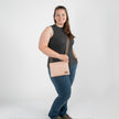 A woman wearing a pink and yellow dotted crossbody bag with brown straps and gold hardware.
