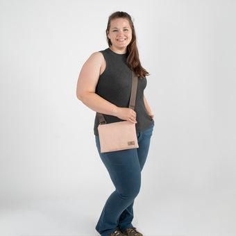 A woman wearing a pink and yellow dotted crossbody bag with brown straps and gold hardware.