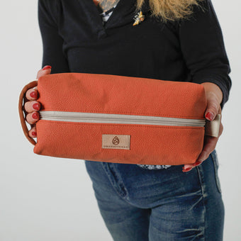 A up-close of tan Unshattered label on orange pebble toiletry kit named after Clark