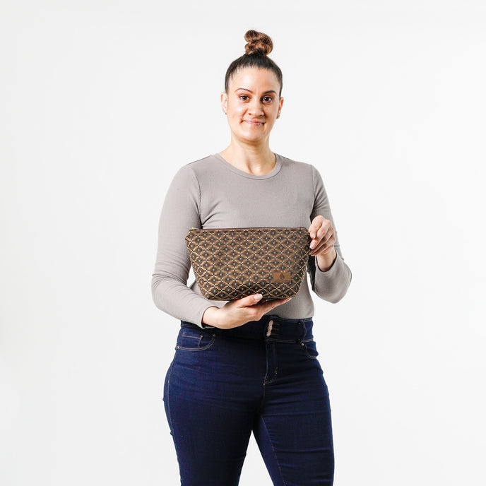 Woman holding a makeup bag with a brown and blue geometric pattern on a white background