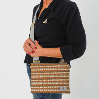 A up-close shot of gray, golden yellows, and earthy browns—interwoven with shimmering gold accents crossbody pouch named after Sarah