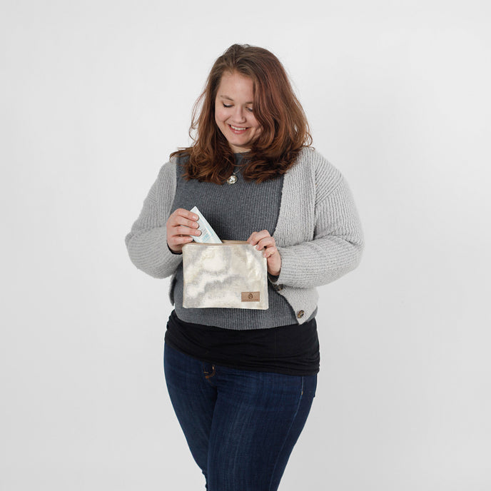 Woman putting product in the Billy pouch made from upcycled materials by Unshattered