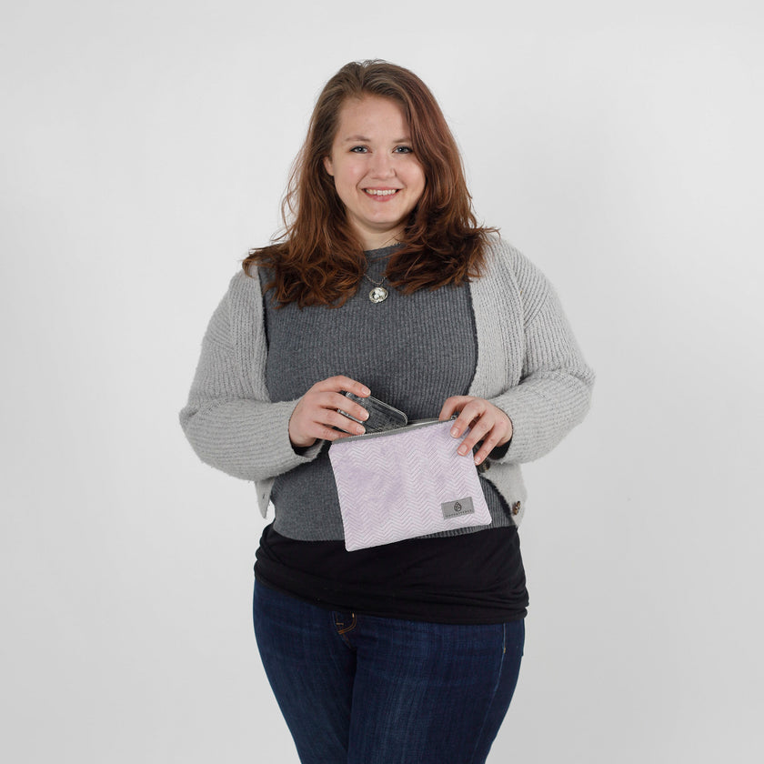 Woman holding a light purple pouch putting an item in it named after Jaimilee