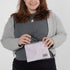 A woman holding a purple plush zip pouch named after Jaimilee