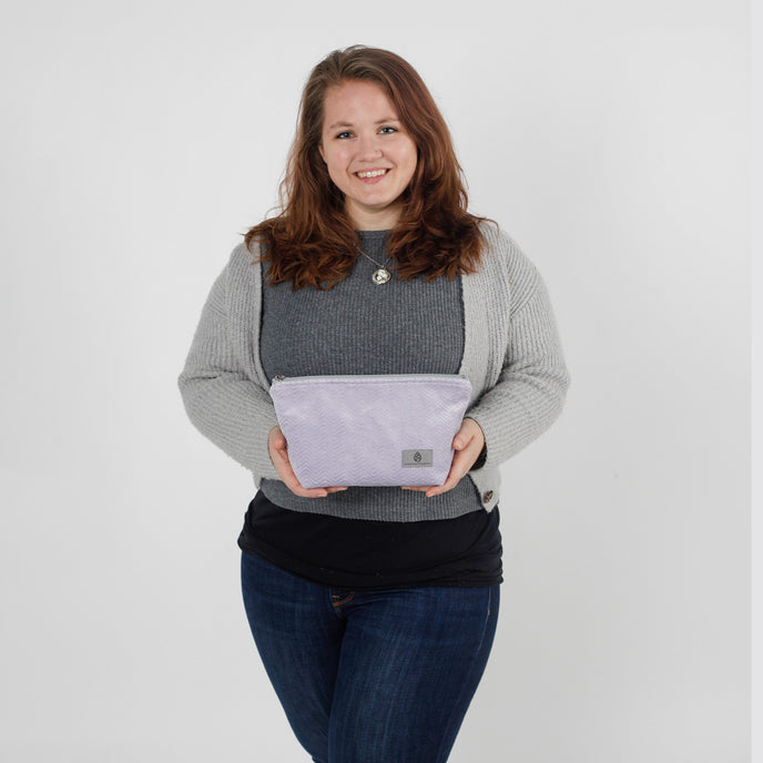 Woman holding a purple makeup with a logo on a white background named after Jamar 
