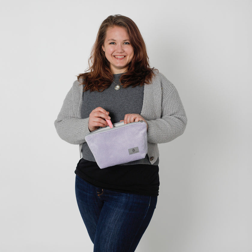 Woman holding a purple makeup against a plain background named after Jamar 