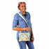 A woman wearing a flower crossbody pouch with tan straps bag named after Leanna