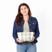 A woman holding a blue plaid makeup bag wearing a green top with jean jacket  named after Mary 