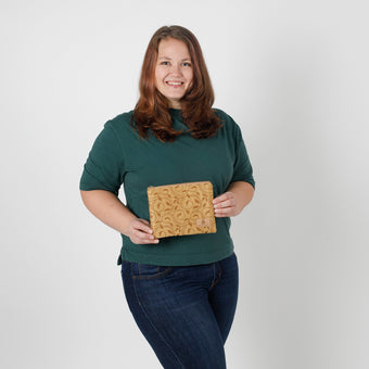Woman holding a yellow pattern pouch against a plain background named after Phil
