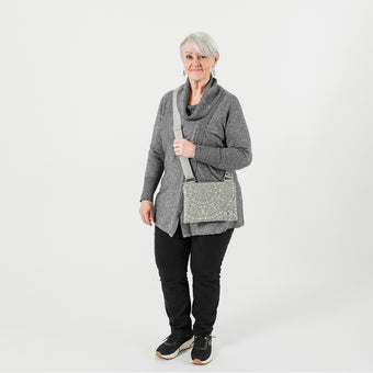A woman wearing a gray and circle design Maggie crossbody pouch with gray strap and silver hardware 