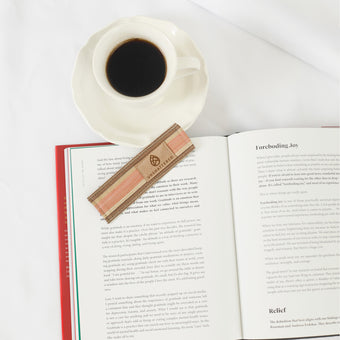 Open book with a cup of coffee and a bookmark on a white surface