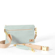 Light blue 3-in-1 crossbody bag named George with a beige belt bag strap and light blue wristlet strap laying on a white table
