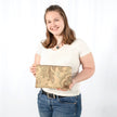 Woman holding a beige clutch with floral patterns against a white background