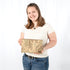 Woman holding a beige clutch with floral patterns against a white background
