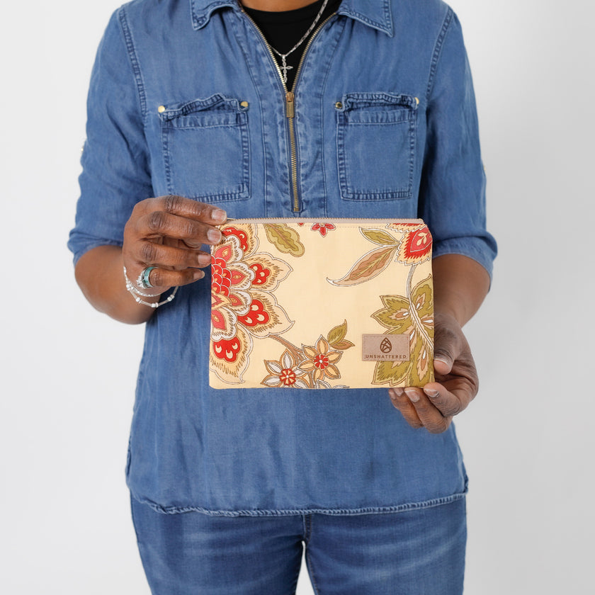 A woman holding a yellow flower design zip pouch named after Liz