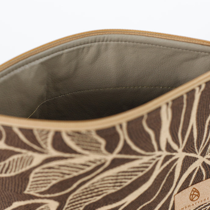 Beige wipe-clean interior of a brown leaf patterned fabric makeup bag on a white background. 