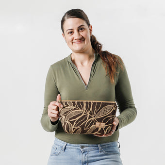 A woman holding an eye-catching brown leaf patterned fabric makeup bag on a white background named after Lizzie