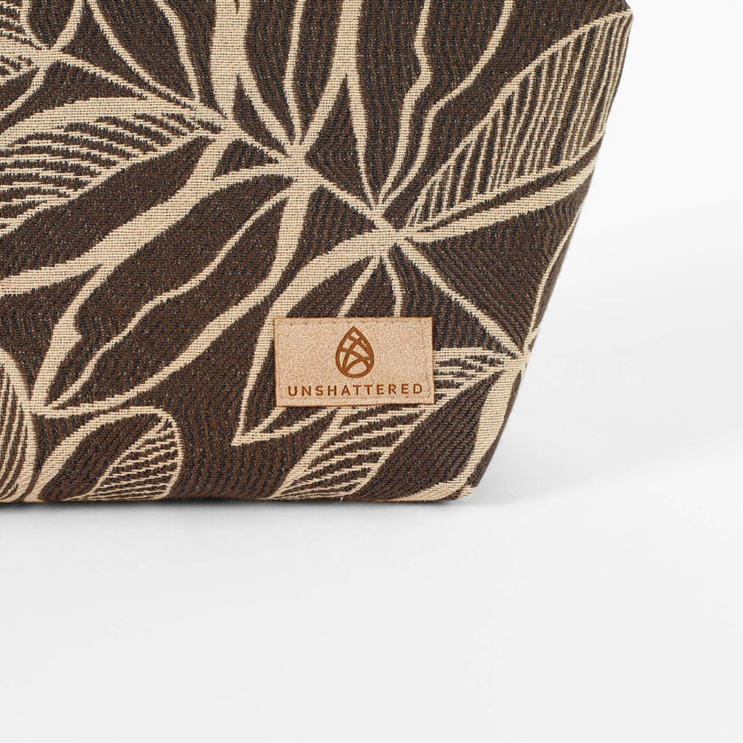 Tan suede Unshattered label on a brown leaf patterned fabric makeup bag named after Lizzie