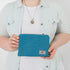 A woman holding a blue zip pouch named after Lorita 