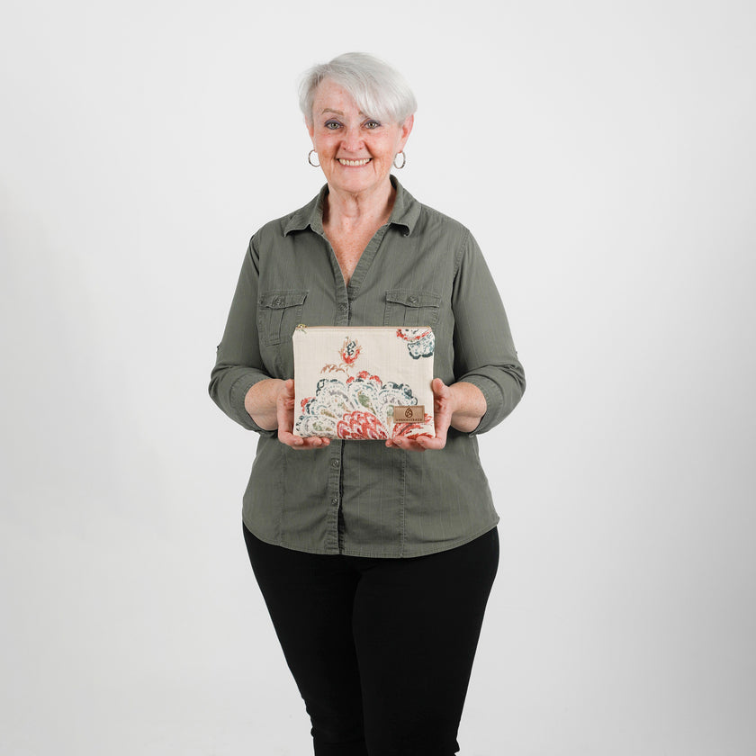 Woman holding a decorative zip pouch against a plain background named after Lyndora