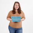 Woman holding a blue wave makeup bag  against a white background