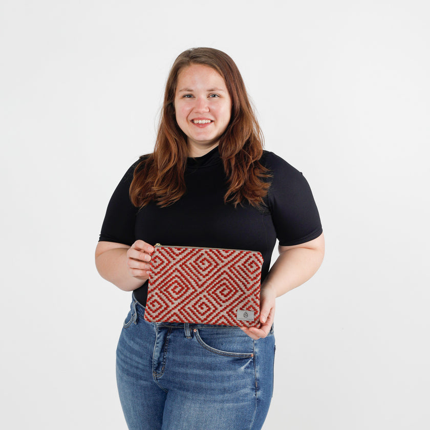 Person holding a red and white patterned large zip pouch against a white background