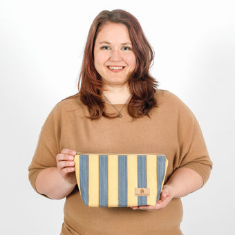 A woman holding a yellow and blue design makeup kit bag named after Malika