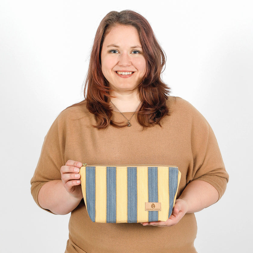 A woman holding a yellow and blue design makeup kit bag named after Malika