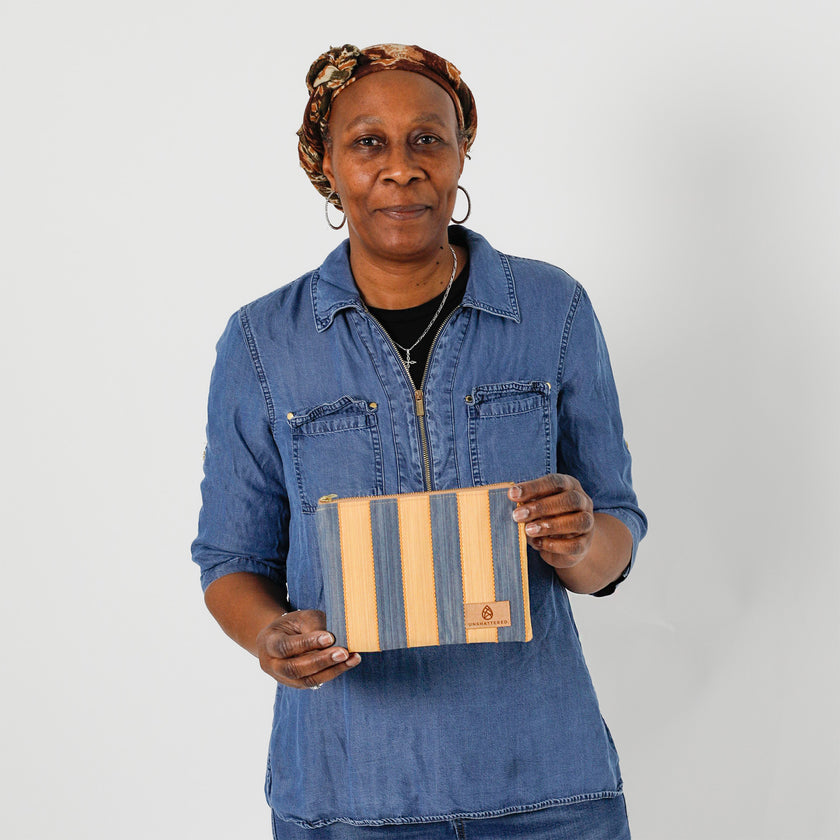 A woman holding a yellow and blue striped zip pouch wearing a jean shirt, named after Marcia 