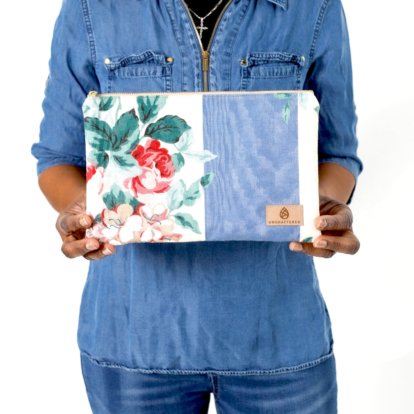 A woman holding a floral and striped pattern large zip pouch wearing a jean shirt bag named after Margaret 