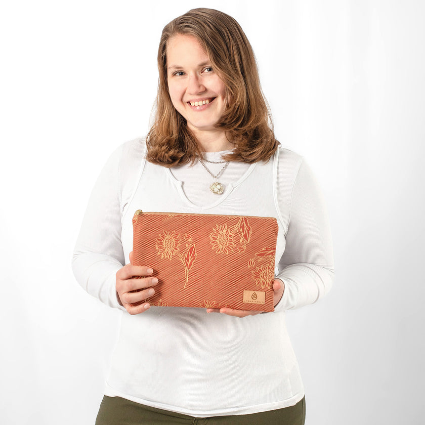 A woman holding a red and yellow daisy pattern large zip pouch 