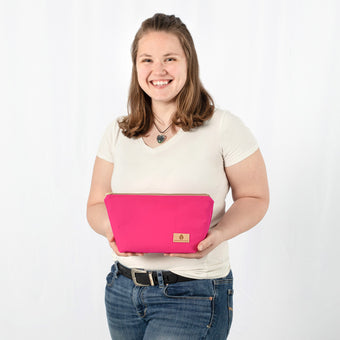 Person holding a hot pink makeup kit against a white background