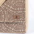 A brown label on a beige and brown circle pattern large messenger bag 