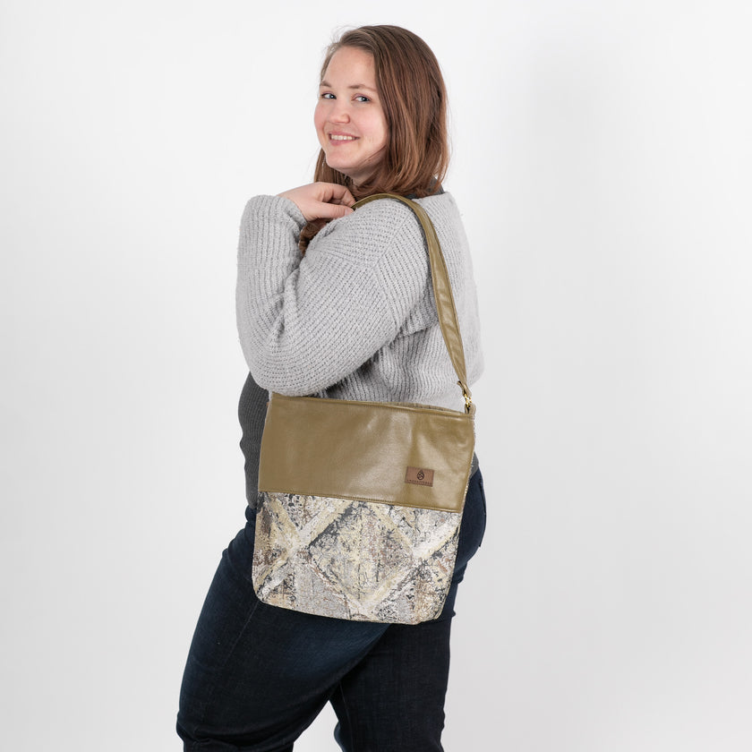 A woman carrying a tote bag with a mixed-metal pattern, featuring upcycled alchemy fabric and luxury leather alternative named after Melissa